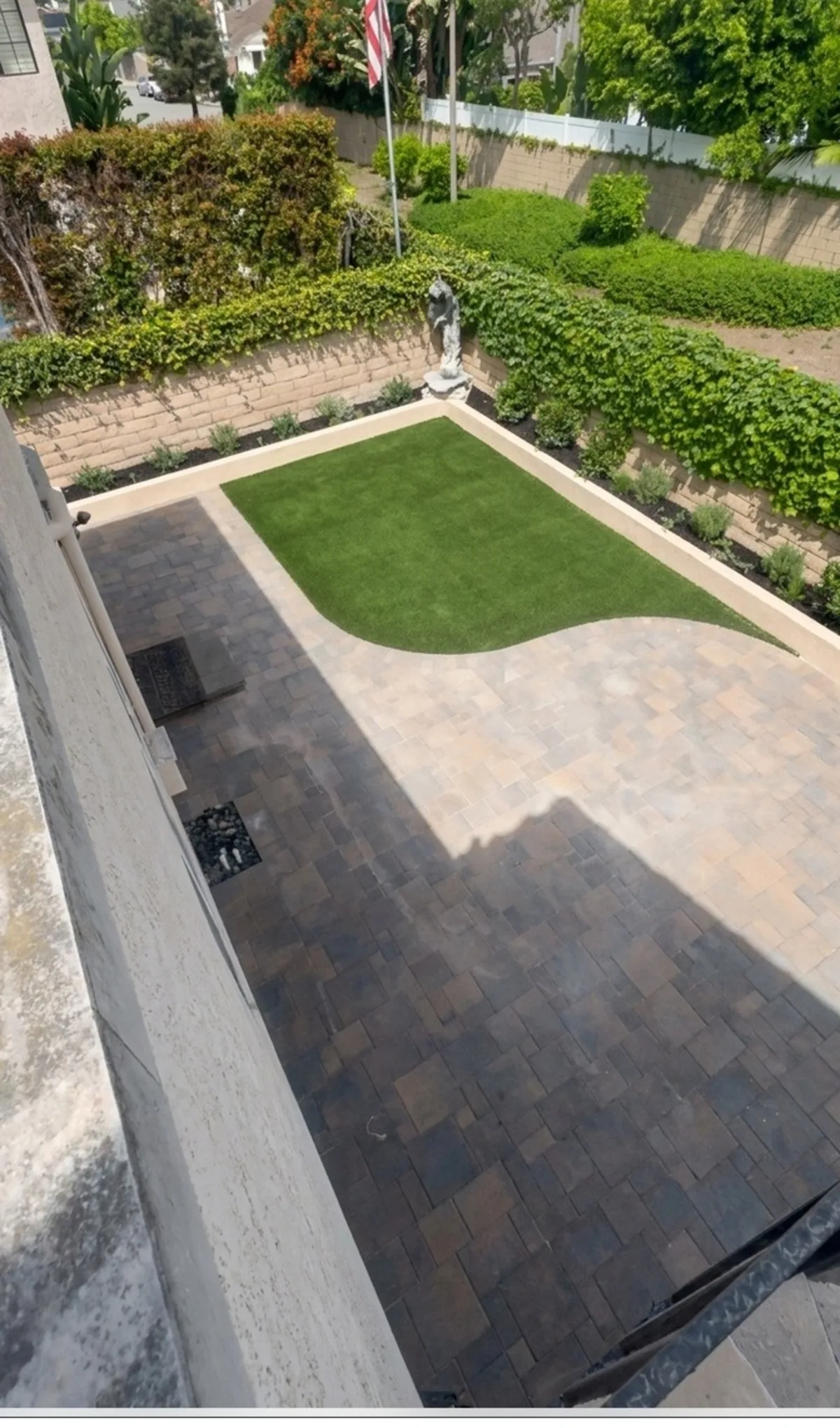 Aerial view of the finished backyard showing the curved lawn meeting the paver court