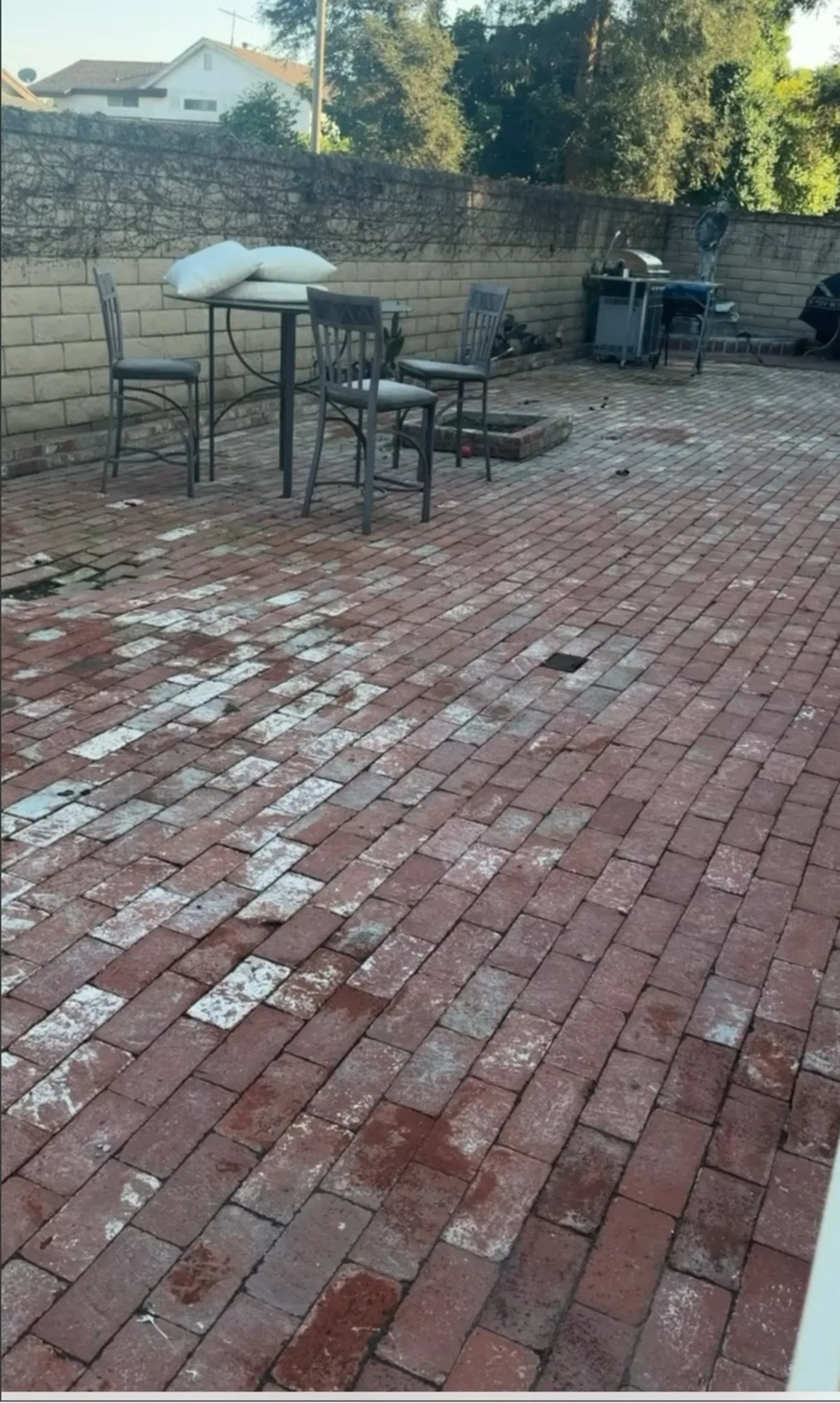 Before: a dated red brick patio with worn pavers, old metal furniture and a bare cinderblock wall