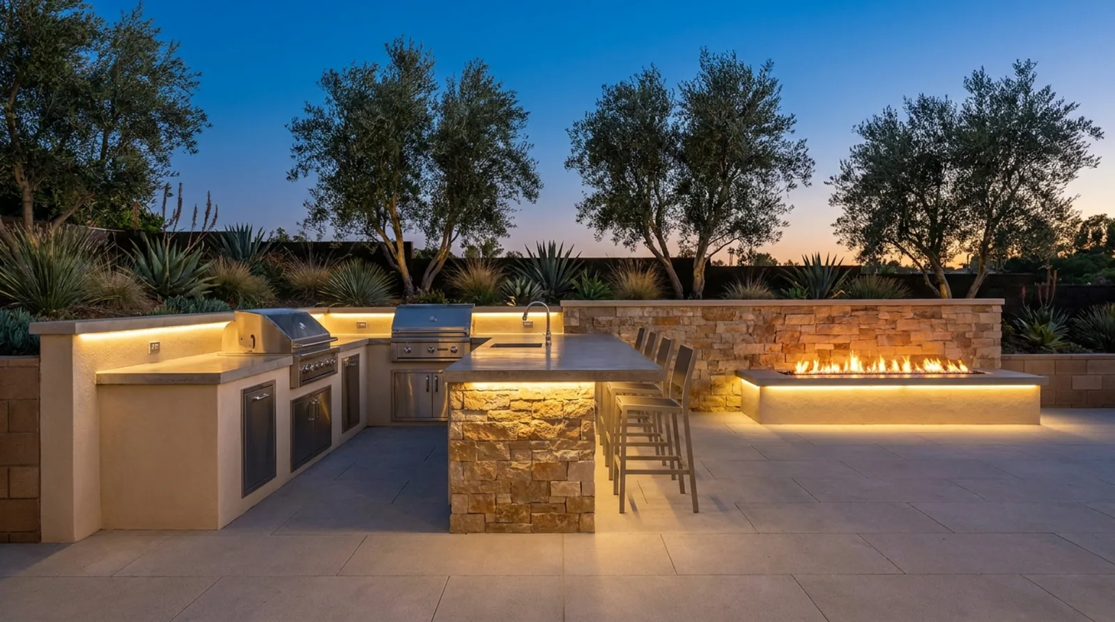 Custom outdoor kitchen with bar seating and linear fire feature at dusk in an Orange County backyard